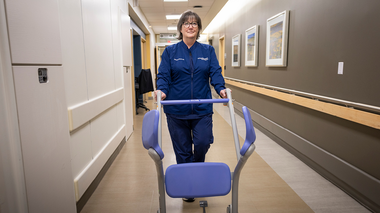 Nurse pushing a piece of equipment through a hallway