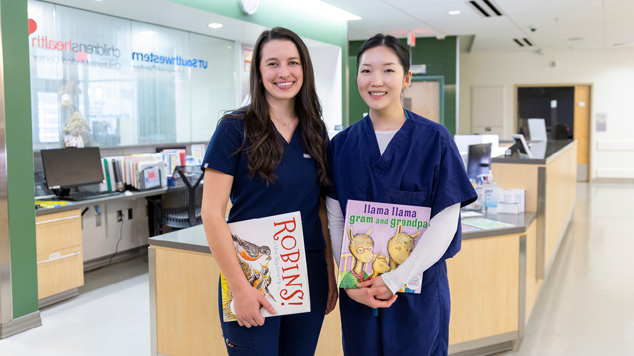 Two nurses standing next to each other holding children's books