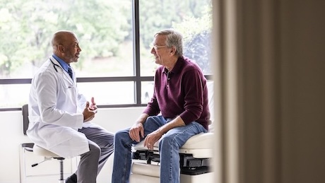 Male doctor talking with senior man in exam room