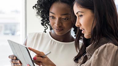 Two women working together and looking at a tablet.