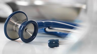 A blue stethoscope lying on a white table.