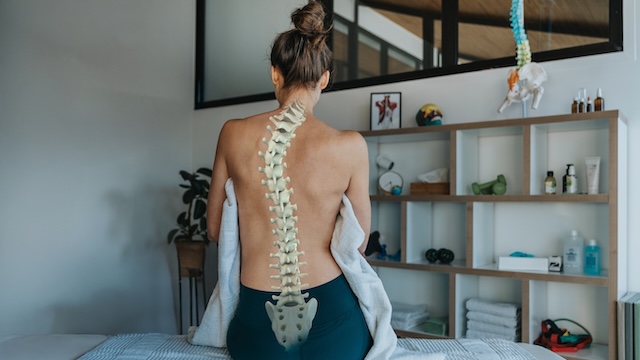 woman with scoliosis sitting in provider office with a superimposed spine on her back.